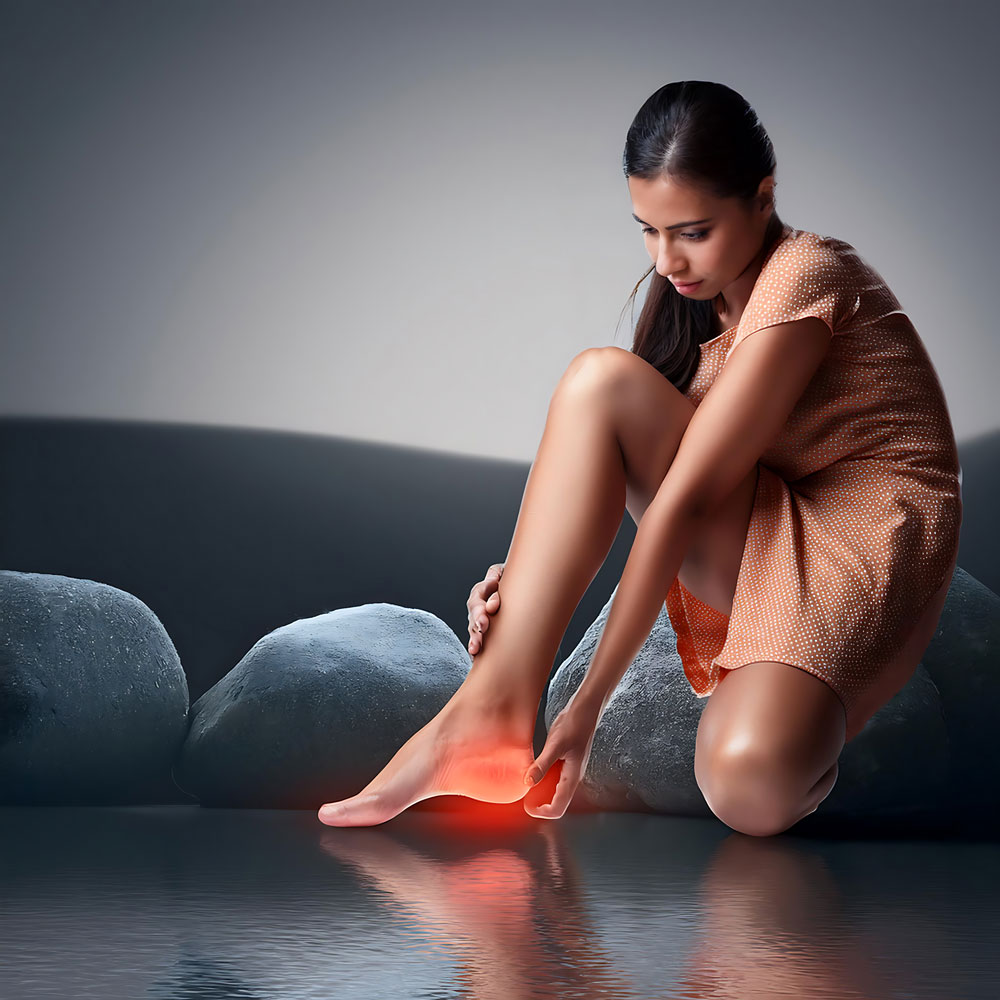 Young woman sitting and grabbing her heel in pain with red glow, common symptom of plantar fasciitis