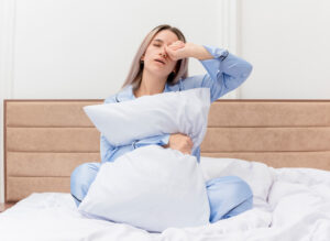 Woman struggling with sleep and chronic pain in bed – sleep hygiene tips for pain relief