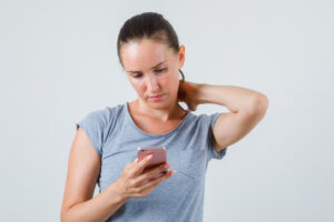 Young female using mobile phone with hand on neck